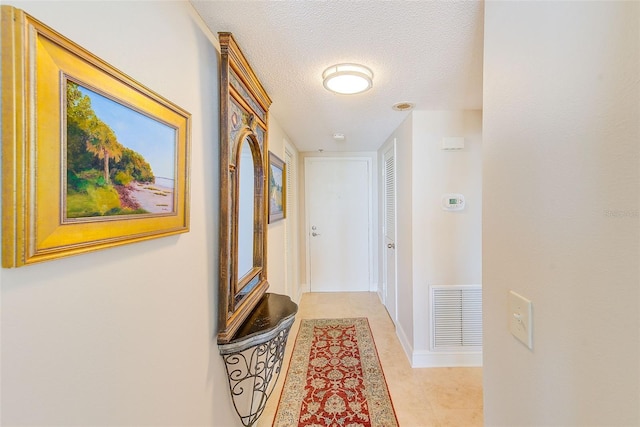 corridor featuring visible vents, baseboards, and a textured ceiling