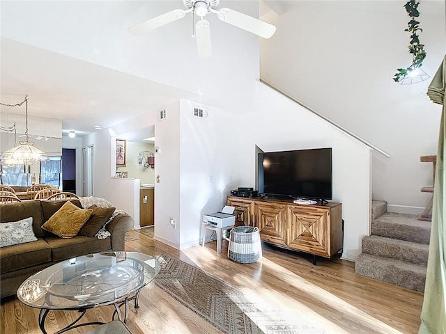 living area with visible vents, baseboards, ceiling fan, light wood-type flooring, and stairs