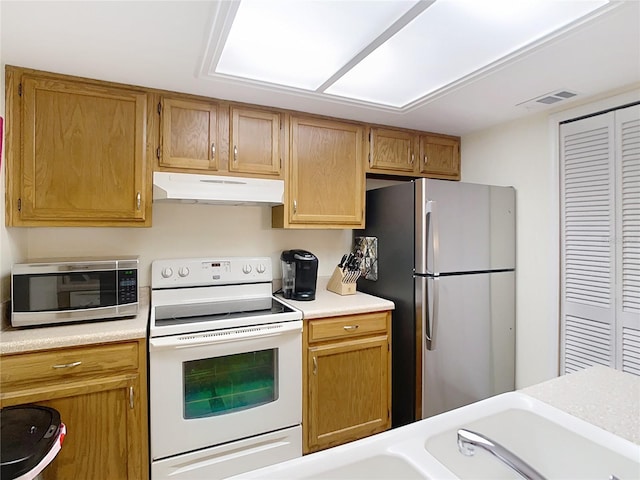 kitchen with brown cabinetry, visible vents, light countertops, appliances with stainless steel finishes, and under cabinet range hood