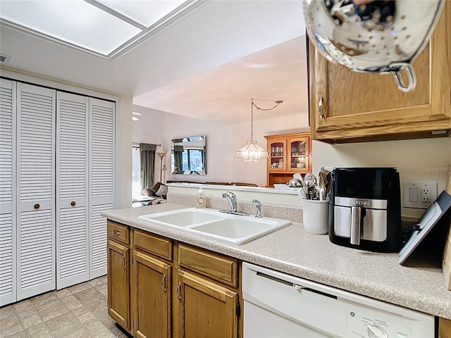 kitchen with light countertops, white dishwasher, and a sink