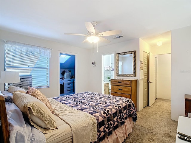 bedroom featuring a ceiling fan, light colored carpet, visible vents, and connected bathroom