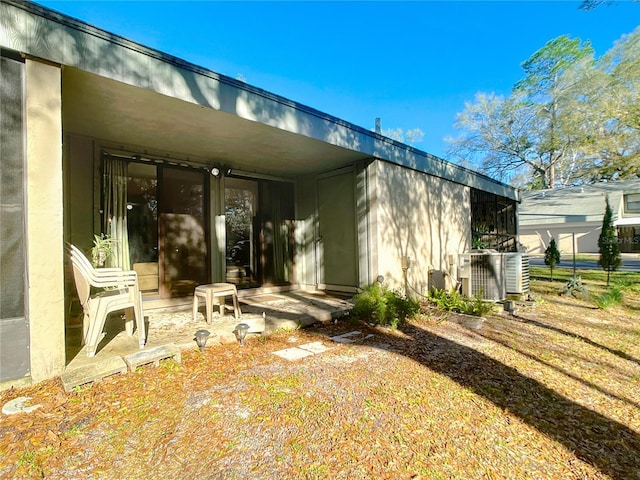 back of property with cooling unit and stucco siding