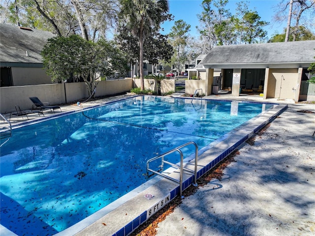 pool with a patio area, an outbuilding, and fence