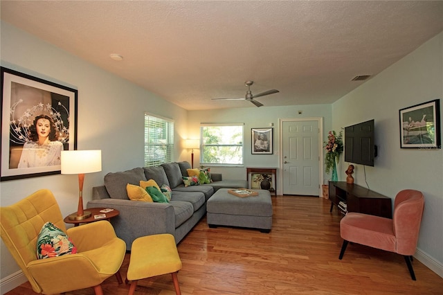 living area featuring ceiling fan, baseboards, a textured ceiling, and wood finished floors