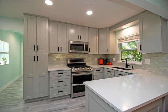 kitchen with light countertops, gray cabinets, appliances with stainless steel finishes, and a sink