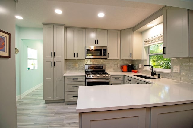 kitchen with light countertops, gray cabinets, appliances with stainless steel finishes, and a sink