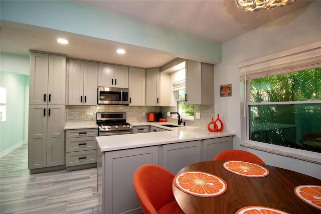 kitchen with a sink, tasteful backsplash, appliances with stainless steel finishes, and gray cabinetry