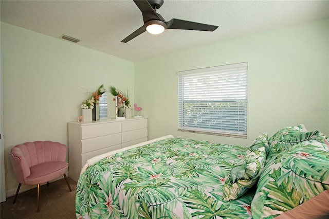 bedroom featuring visible vents, carpet, ceiling fan, and a textured ceiling