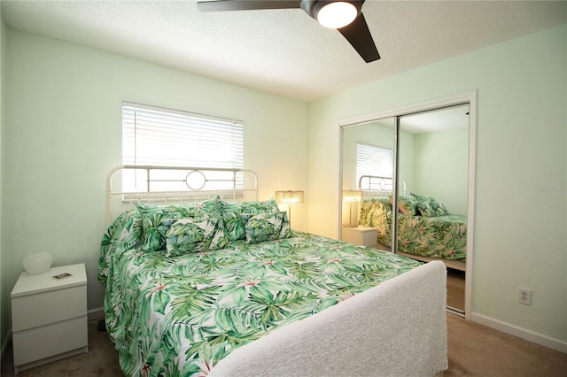 carpeted bedroom with a closet, multiple windows, a textured ceiling, and baseboards