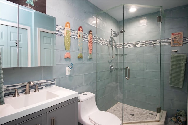 bathroom with vanity, decorative backsplash, a shower stall, tile walls, and toilet