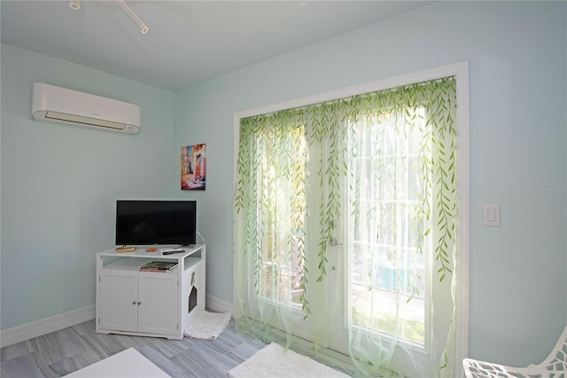 interior space with multiple windows, baseboards, and a wall mounted air conditioner