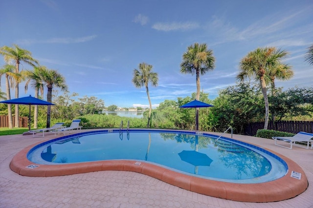 community pool with a patio area and fence