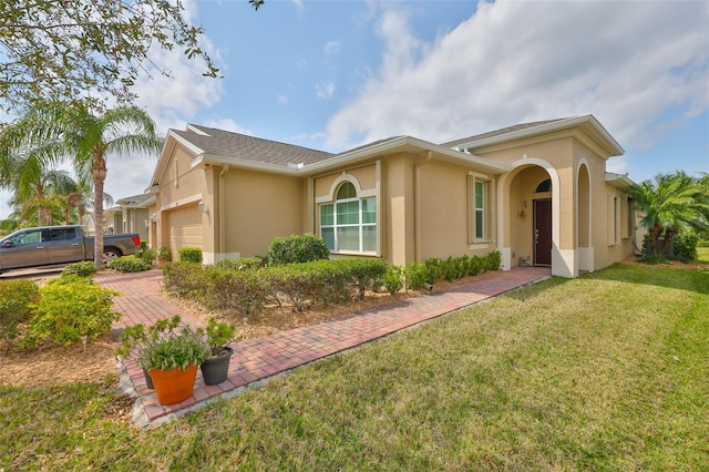 ranch-style house featuring stucco siding, a front yard, decorative driveway, and a garage