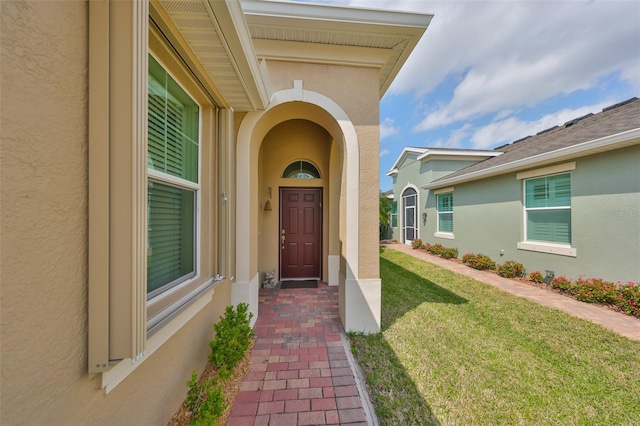 property entrance with a yard and stucco siding