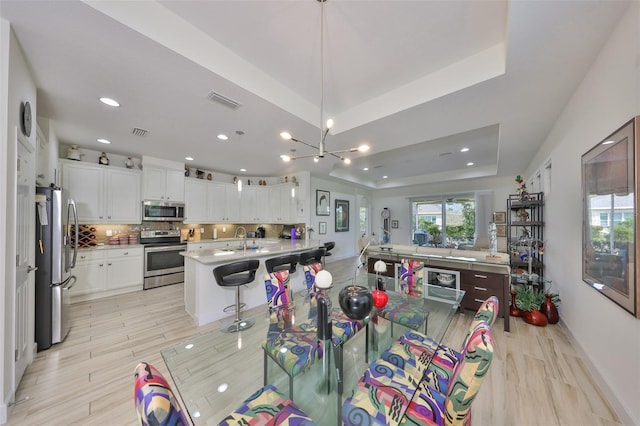 807 Chipper Dr, Sun City Center, FL 33573 - dining space featuring visible vents, light wood-style floors, and a tray ceiling