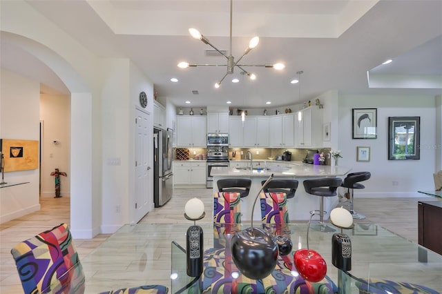 807 Chipper Dr, Sun City Center, FL 33573 - kitchen featuring light countertops, arched walkways, stainless steel appliances, a raised ceiling, and a sink