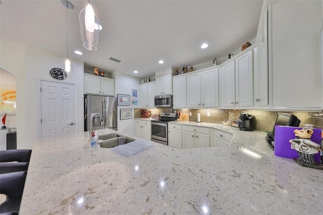 807 Chipper Dr, Sun City Center, FL 33573 - kitchen with visible vents, light stone counters, stainless steel appliances, white cabinetry, and a sink