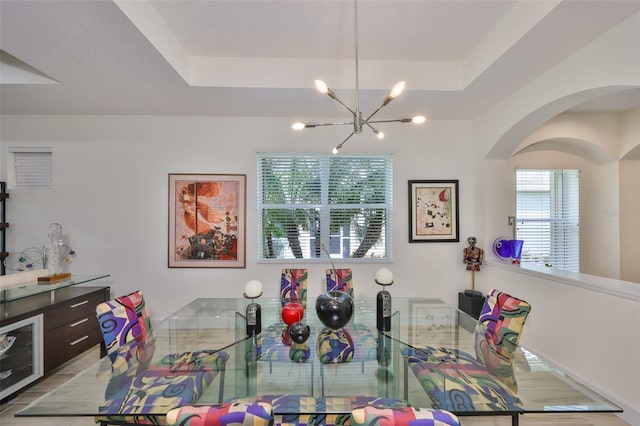 807 Chipper Dr, Sun City Center, FL 33573 - dining room featuring an inviting chandelier, a tray ceiling, and arched walkways