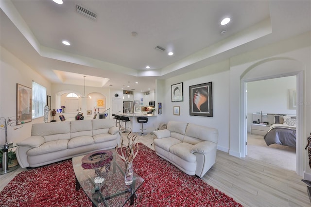 807 Chipper Dr, Sun City Center, FL 33573 - living room featuring a tray ceiling, baseboards, visible vents, and light wood finished floors