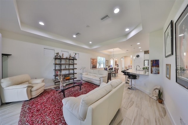 807 Chipper Dr, Sun City Center, FL 33573 - living area with a tray ceiling, baseboards, visible vents, and light wood finished floors