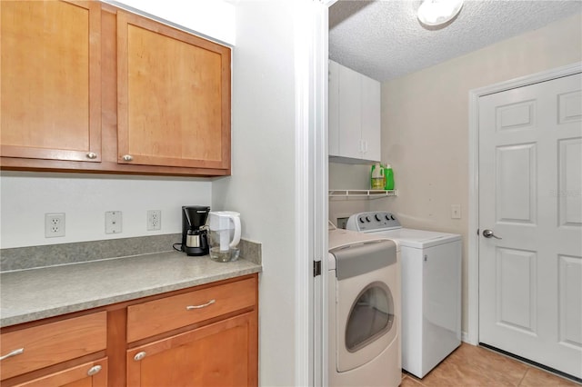 laundry room with light tile patterned floors, cabinet space, a textured ceiling, and washer and clothes dryer