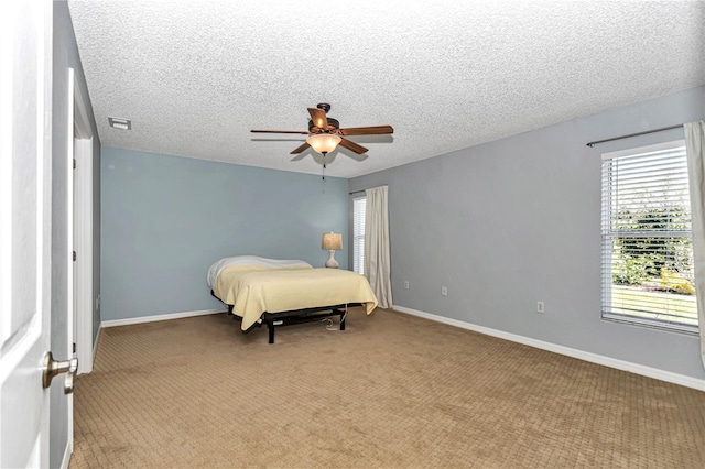 bedroom featuring visible vents, light carpet, a ceiling fan, a textured ceiling, and baseboards