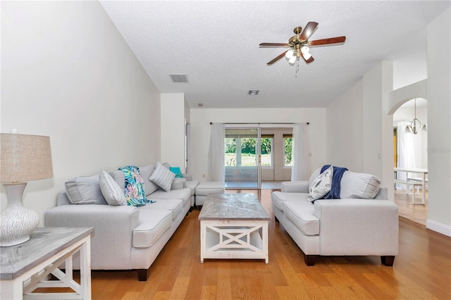 living area featuring arched walkways, visible vents, light wood finished floors, and ceiling fan