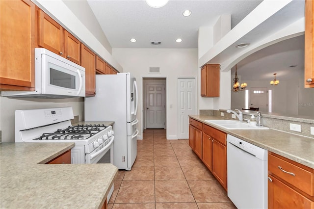 kitchen featuring visible vents, light countertops, arched walkways, white appliances, and a sink