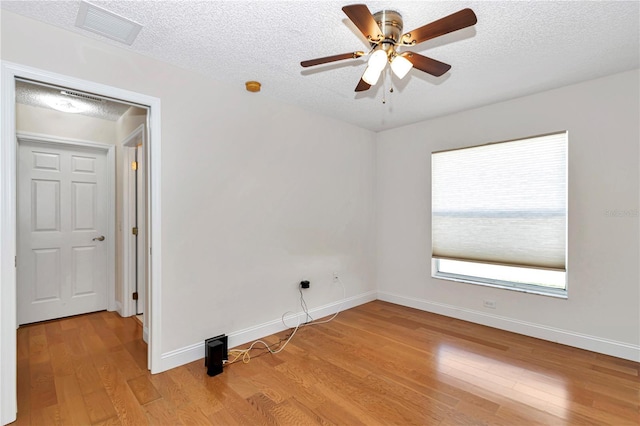 unfurnished room with visible vents, a textured ceiling, light wood-type flooring, and baseboards