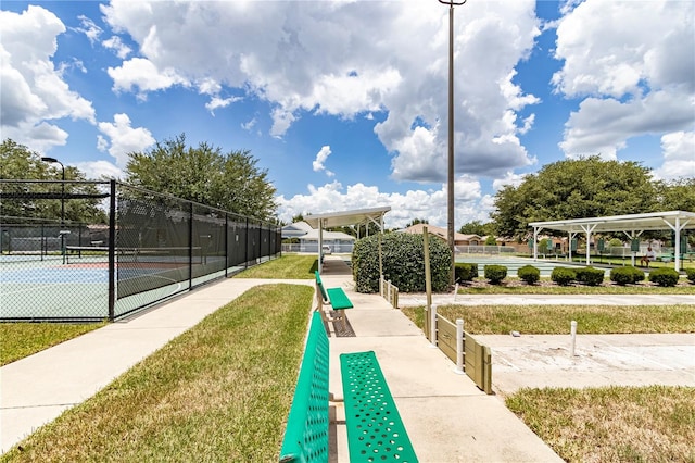 surrounding community featuring a lawn, a tennis court, and fence