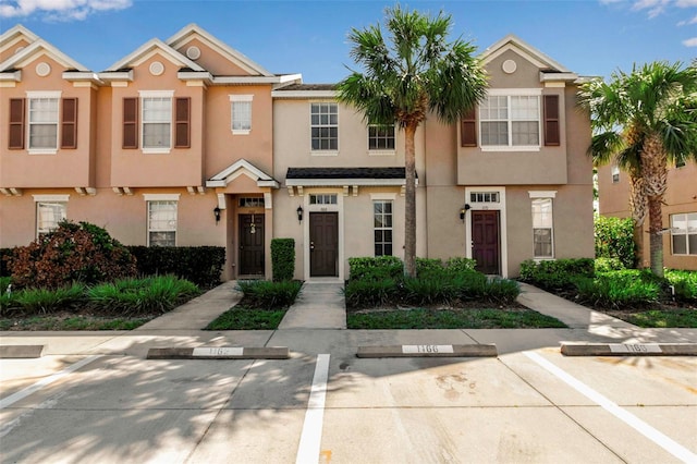 townhome / multi-family property with uncovered parking and stucco siding