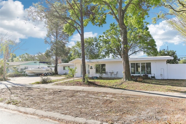 single story home with stucco siding, concrete driveway, a front yard, and fence