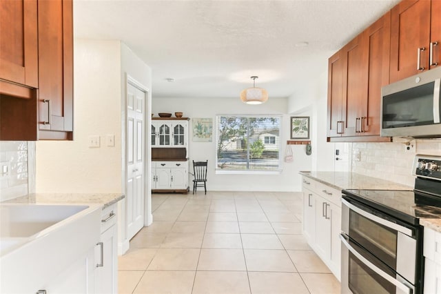 kitchen featuring backsplash, decorative light fixtures, light stone counters, appliances with stainless steel finishes, and light tile patterned flooring