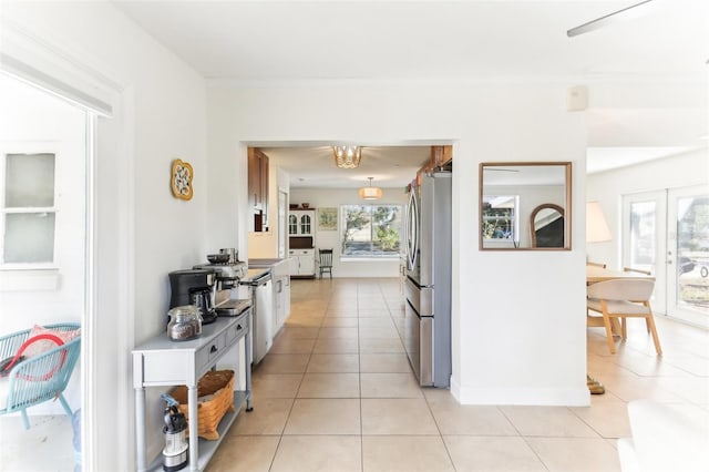 kitchen featuring light tile patterned flooring, baseboards, freestanding refrigerator, and ornamental molding