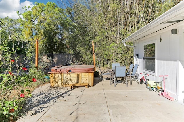 view of patio / terrace with a fenced backyard, outdoor dining space, and a hot tub