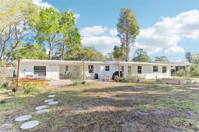 back of house with a patio area, a hot tub, and a carport