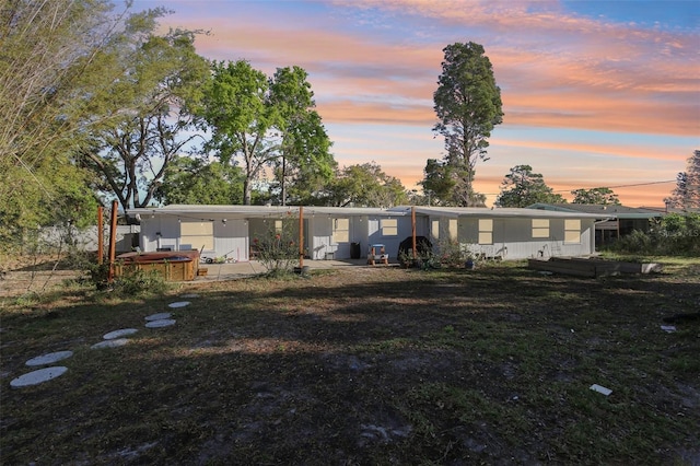 back of house with a patio area, an attached carport, a yard, and a hot tub