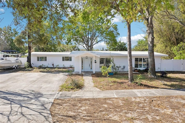 ranch-style house with stucco siding, concrete driveway, and fence