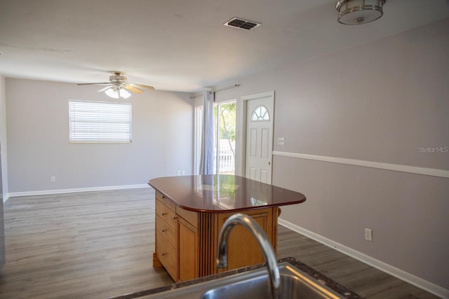 kitchen with visible vents, wood finished floors, baseboards, and ceiling fan