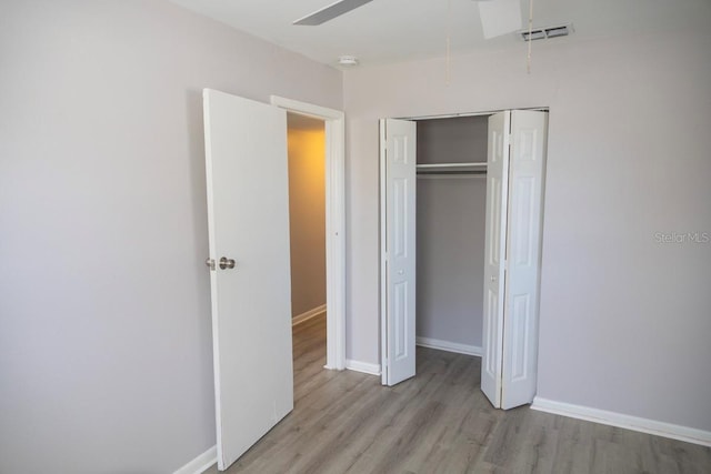 unfurnished bedroom featuring wood finished floors, visible vents, baseboards, attic access, and a closet