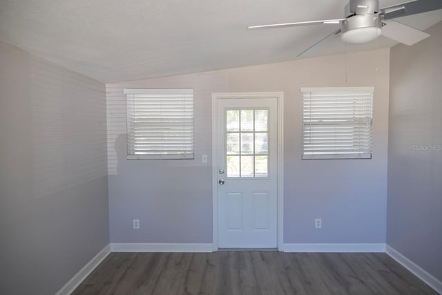 doorway with wood finished floors, baseboards, lofted ceiling, and ceiling fan