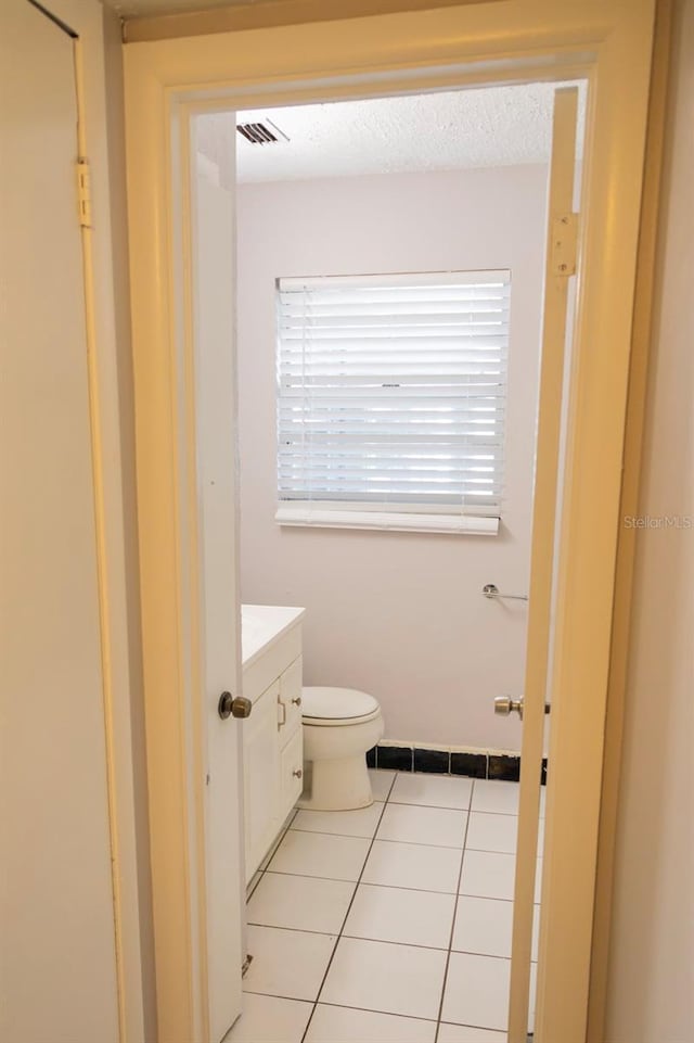 bathroom with tile patterned floors, visible vents, toilet, a textured ceiling, and vanity