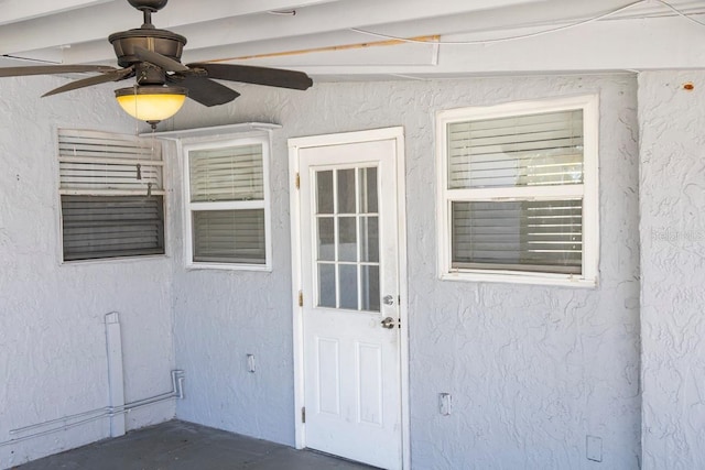 view of exterior entry featuring stucco siding and ceiling fan