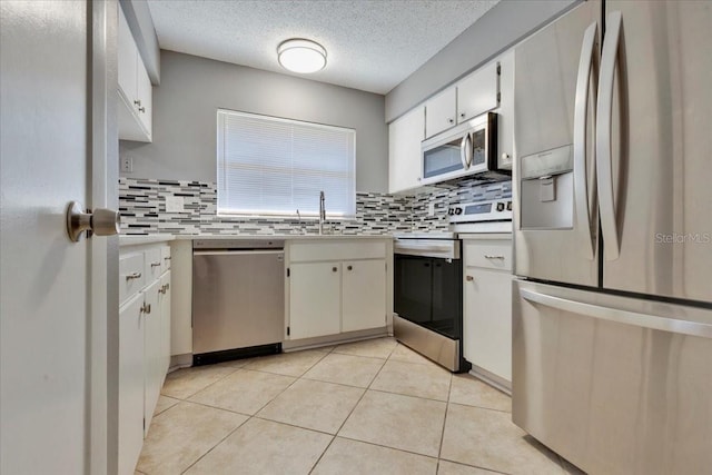 kitchen with a sink, tasteful backsplash, stainless steel appliances, light countertops, and light tile patterned floors