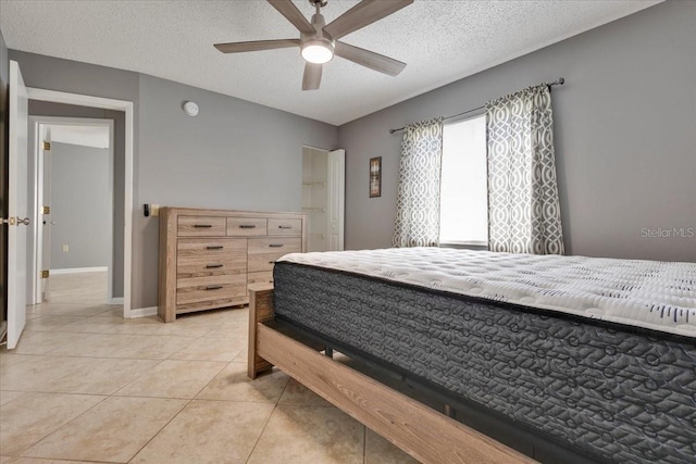 bedroom featuring light tile patterned floors, ceiling fan, a textured ceiling, and baseboards