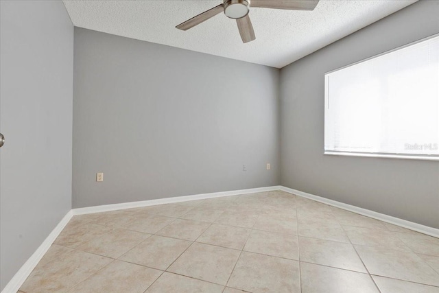 empty room with light tile patterned flooring, baseboards, a textured ceiling, and a ceiling fan