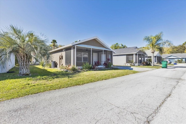 view of front of property featuring stucco siding, driveway, a front lawn, and a sunroom