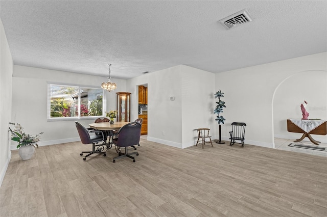 dining room featuring visible vents, a notable chandelier, a textured ceiling, light wood-style floors, and baseboards