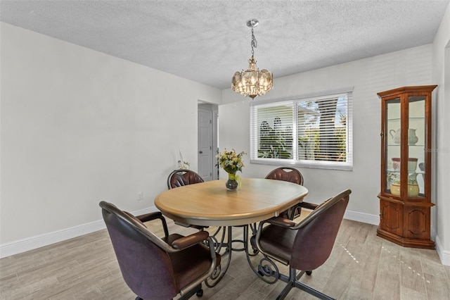 dining room featuring baseboards, an inviting chandelier, and light wood finished floors