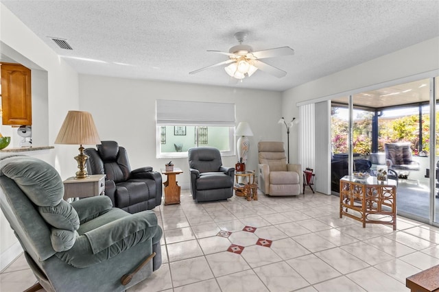 living area with a wealth of natural light, visible vents, ceiling fan, and light tile patterned floors